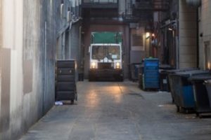 garbage truck in urban alley vibrations above restaurant wine cellar