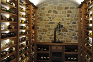 Stone finish home wine cellar with wine bottles beautifully arranged on wooden wine racks.