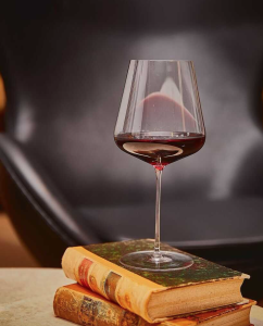 Bordeaux wine glass partly filled with red wine sitting on top of a book.